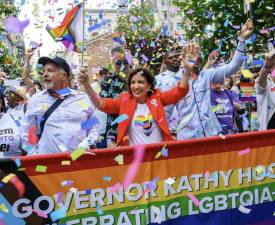 Gov. Kathy Hochul wears an MTA Pride heart shirt at the Pride Parade of June 30— the same date congestion pricing was to begin—as rainbow confetti falls all around her.