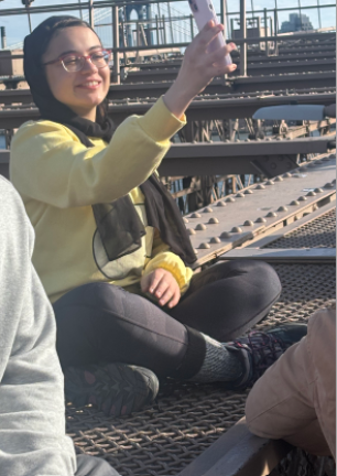 Sitting on the side of the pedestrian archway to get a sunny day selfie on the Brooklyn Bridge