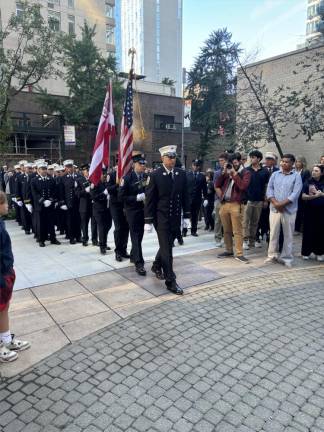 The color guard strides into the vest pocket memorial park on W. 48th St. across from the firehouse on the corner of Eighth Ave.