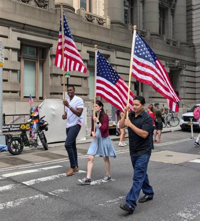 Grand Marshal and Assembly Member Charles D. Fall (left) whose district includes part of lower Manhattan as well as Staten Island and parts of Brooklyn, carries an American flag in the Independence Day parade in lower Manhattan on July 4.