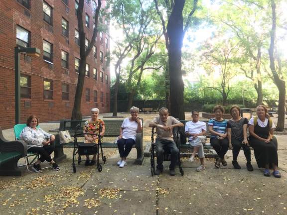 LIRA residents relax in a private courtyard attatched to their housing complex is adjacent to Elizabeth Street Garden. The city wants to take it over and merge it to create a new green space when it builds an affordable housing complex where the garden now stands.