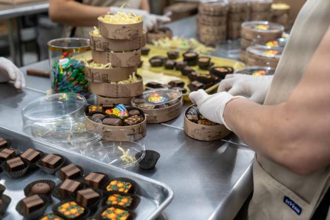 The packaging team packs chocolates in a box, adding some final touches to complete the process.