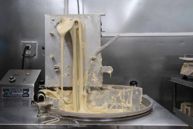 A tempering machine with white chocolate. The machine helps cool, heat, and mix the chocolate while also keeping it fresh for the day.