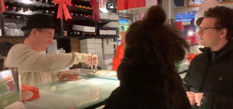 John DeLutro (left), behind the counter at Cafe Palermo is still serving up some of the best cannolis in Little Italy to his customers.